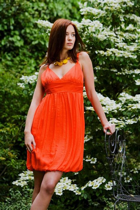 A Woman In An Orange Dress Is Posing For The Camera