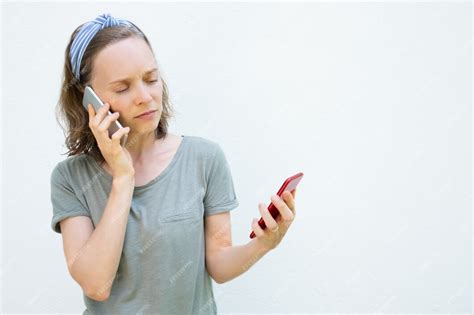 Free Photo Serious Busy Young Woman Using Two Mobile Phones