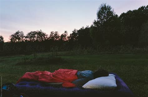 Man Sleeping Outdoors On An Air Mattress At Sunset By Stocksy