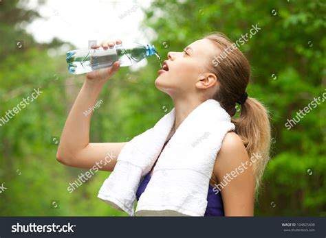 Young Beautiful Woman Drinking Water After Fitness Exercise Outdoors