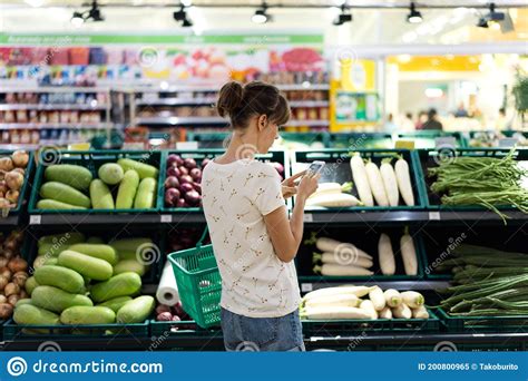 Woman Using Mobile Phone While Shopping In Supermarket Stock Image