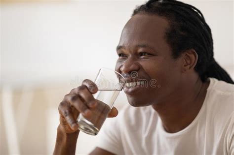 Closeup Shot Of Smiling Handsome Black Man Drinking Water From Glass