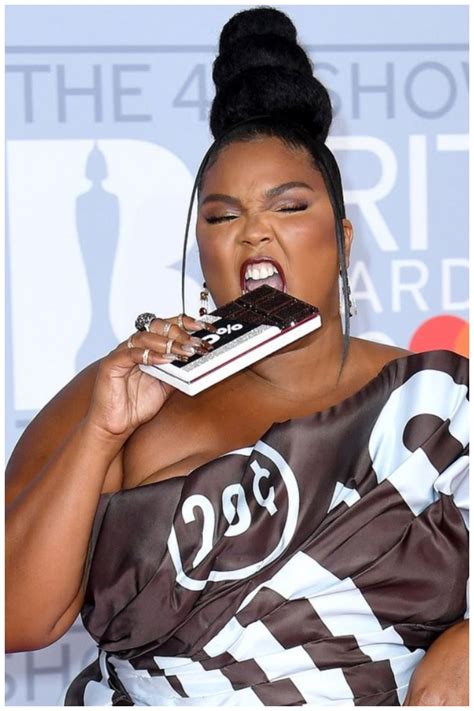 A Woman Is Biting Into A Piece Of Cake With Her Mouth Wide Open And Holding It In One Hand