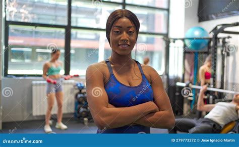 Smiling Black Woman Poses Arms Crossed In Gym Flexes Muscles Stock