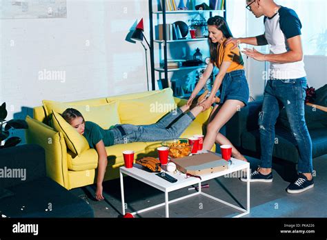 Mädchen Ziehen Betrunkene Freundin Schlafen Auf Dem Sofa Nach Home Party Stockfotografie Alamy