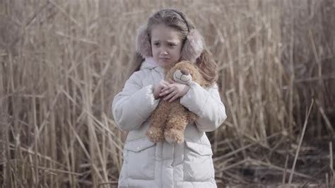 Portrait Of Lost Caucasian Little Girl With Teddy Bear Crying Outdoors
