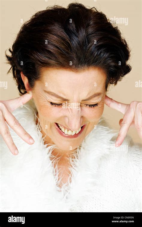 dark haired woman in her forties puts her index fingers into her ears