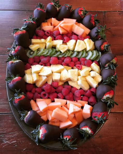 A Platter Filled With Fruits And Chocolates On Top Of A Wooden Table