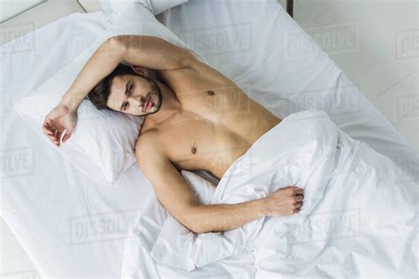 Top View Of Handsome Shirtless Sexy Man Lying On White Bed Stock