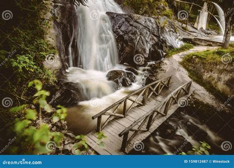 Horizontal Shot Of A Waterfall Flowing Into A River With A Small Wooden