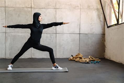 Young Muslim Woman In Hijab Doing Exercise During Yoga Practice Stock