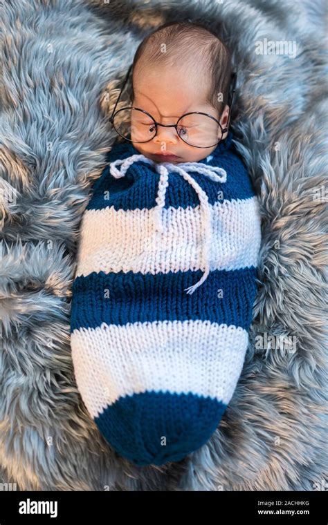 Newborn Baby Boy Wearing Glasses Sleeping And Swaddled In A Knit Wrap