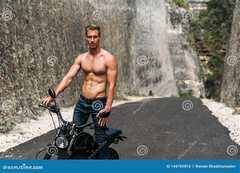 Muscular Man Riding On Motorbike On The Road Between The Rocks Stock