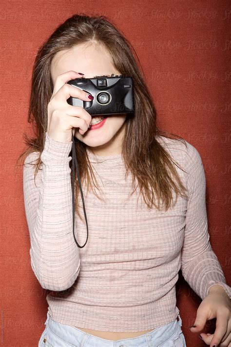 cheerful brunette holding film camera in front of her face by stocksy