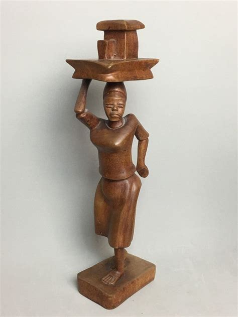 A Wooden Statue Holding A Tray On His Head