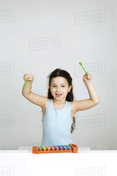 Little Girl Playing Xylophone Arms Raised Looking At Camera Stock