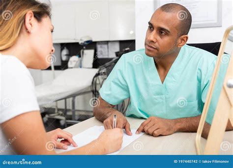 Male Beautician Filling Medical Card With Woman Client Stock Photo