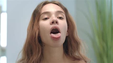 Young Woman With Opened Mouth Looking Tongue And Throat In Mirror In