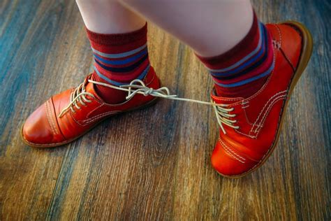 Premium Photo Woman With Shoelaces Tied Together Red Funny Shoes On Wooden Background