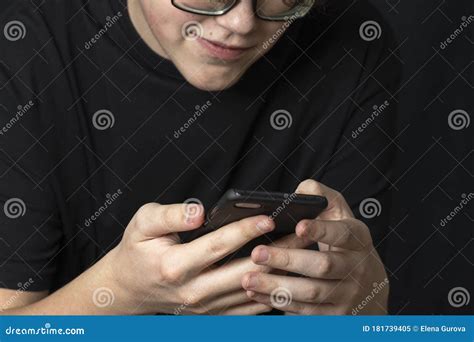 Un Adolescent En Verres Regarde Un Smartphone Et Des Sourires Image Stock Image Du Personne