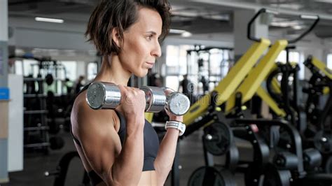 Sporty Mature Woman Is Making Biceps Exercise With Dumbbells In Gym