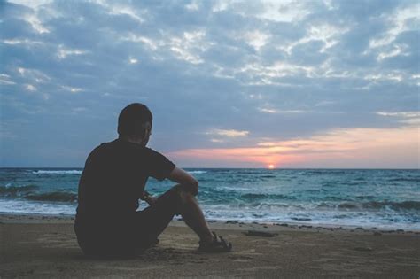 Premium Photo Alone Man Looking At The Sunset On A Beach