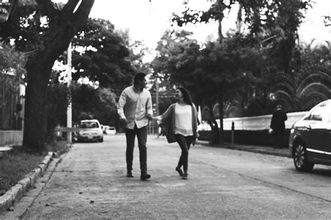 Black And White Photograph Of Two People Walking Down The Street With