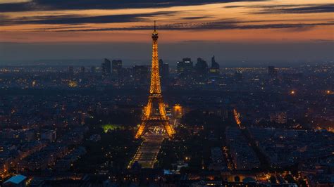Yellow Lighting Eiffel Tower And Paris City With Cloudy Sky Background