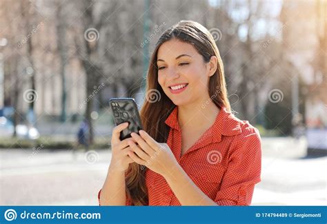 Pretty Beautiful Young Woman With Long Hair Messaging On The Smart Phone In City Street Smiling