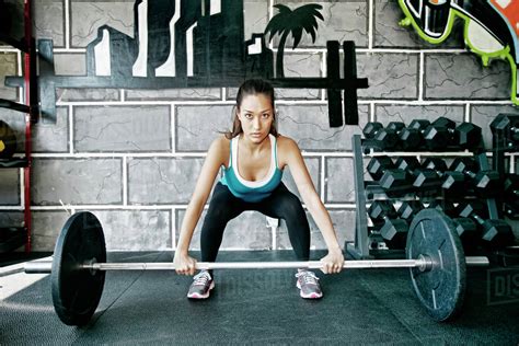 Mixed Race Woman Lifting Weights In Gym Stock Photo Dissolve