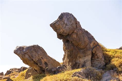 Two Large Rocks Sitting On Top Of A Grass Covered Hillside
