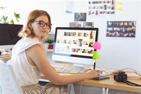 Female Graphic Designer Working On Graphic Tablet At Desk In Office