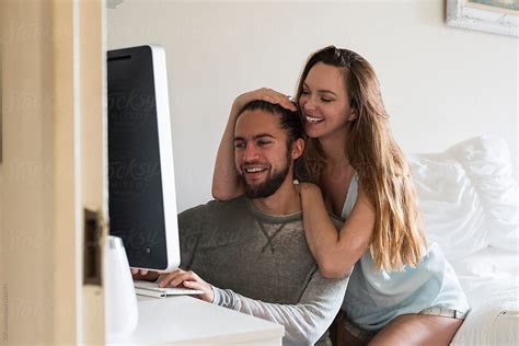 Young Happy Couple Using Computer Together At Home By Simone Wave
