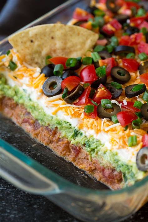 the best 7 layer dip made with seasoned refried beans guacamole sour cream cheese olives