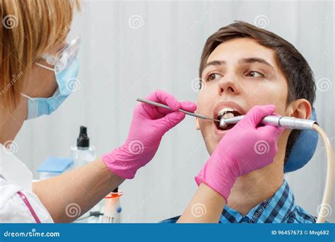 Female Dentist Is Treating A Patient Tooth In Dental Office Wit Stock