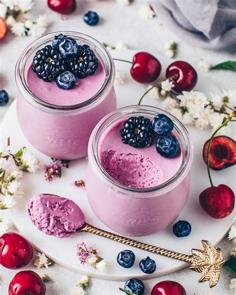 Two Jars Filled With Blueberries And Raspberry Ice Cream On Top Of A White Plate