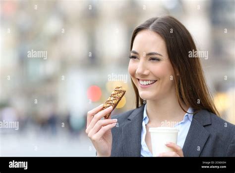 Happy Executive Woman Holding Takeaway Coffee Cup And Cereal Bar In The