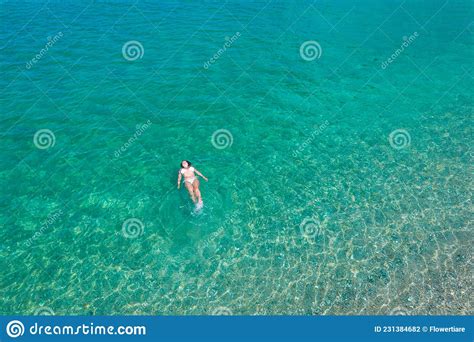 Young Woman In A Swimsuit Lying On Sea Water On The Beach View From Above Top Drone View