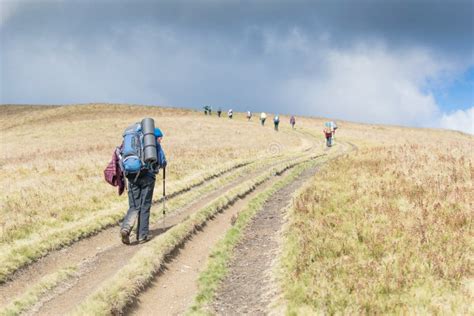 A Group Of People With Backpacks Hiking In The Mountains Stock Photo
