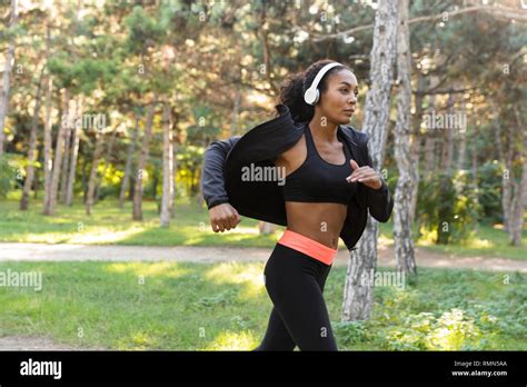 Image Of Slim Woman 20s Wearing Black Tracksuit And Headphones Working