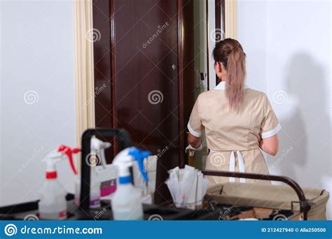 A Uniformed Maid Opens The Door Of A Hotel Room Cleaning And