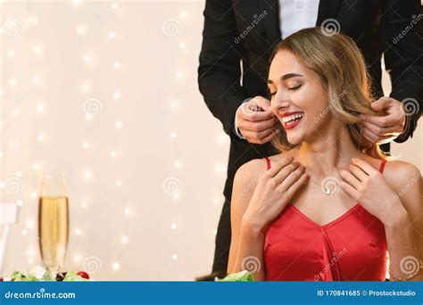 Man Putting Golden Necklace On Girlfriend S Neck At Date In Restaurant