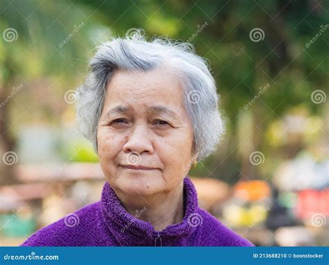 Portrait Of Elderly Asian Woman With Short Gray Hair And Standing Smiling And Looking At The