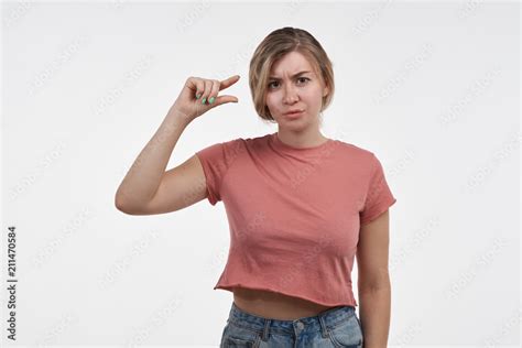 A Beautiful Woman With A Stylish Hairstyle Gestures In The Studio And Shows The Size Of