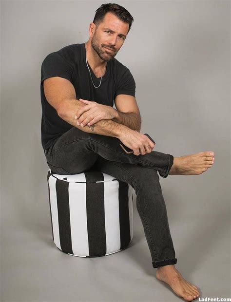 A Man Sitting On Top Of A Black And White Striped Stool With His Legs
