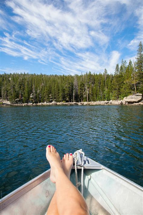 Females Feet On A Fishing Boat In A Lake With A View Of Trees And