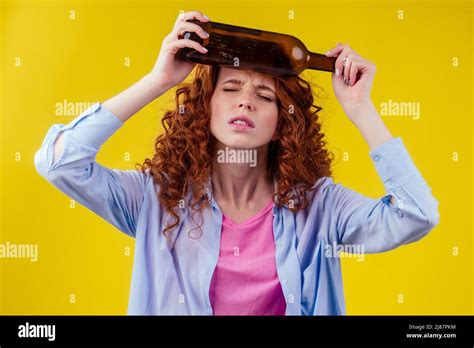 Curly Redhead Ginger Woman Drinking Beer And Feeling Bad Mood In Csudio Yellow Background Stock