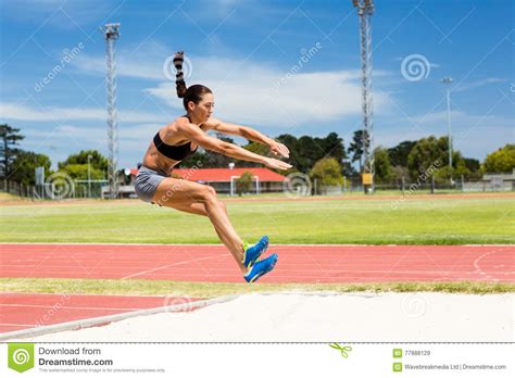 atleta de sexo femenino que realiza un salto de longitud imagen de archivo imagen de completo
