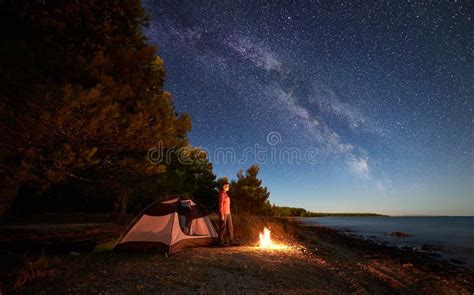 Woman Having A Rest At Night Camping Near Tourist Tent Campfire On Sea