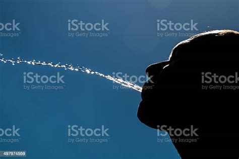 Hombre En Silueta Escupir Agua Con Cielo Azul De Fondo Foto De Stock Y